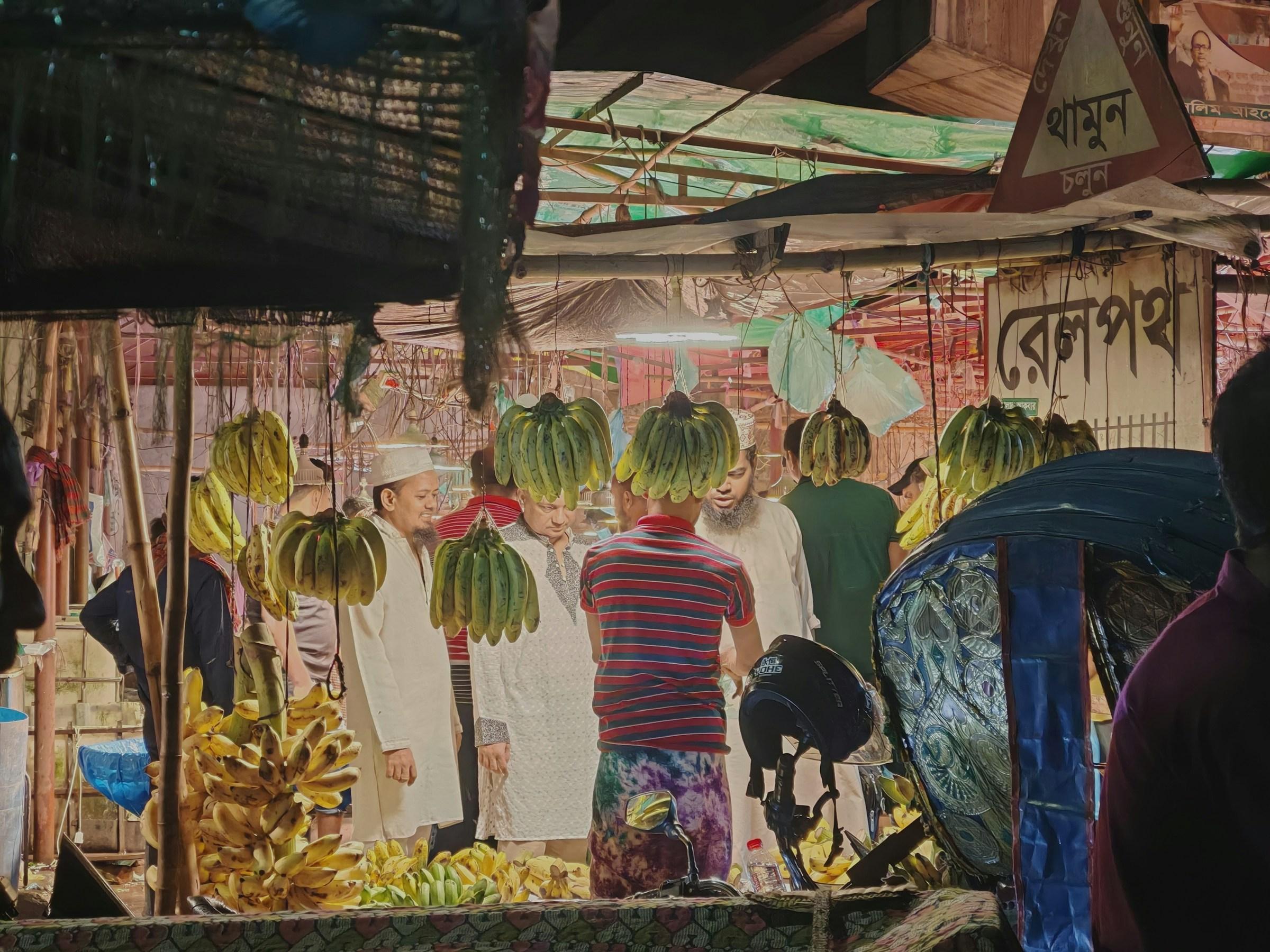 রাতের বাজারে আলো জ্বলা দোকানে কলা কিনছেন ক্রেতারা